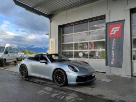 Ein silbernes Porsche 911 Cabriolet parkt vor der Garage neben der Fastlane Tuning Schweiz Flagge
