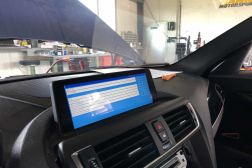 Profitieren Sie von der neuesten BMW Software und Funktionen. Bild einer BMW Headunit während des Update-Vorgangs. Blauer Bildschirm mit Text.