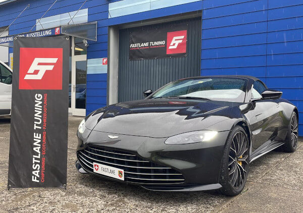 Ein smaragdgrün-schwarzer Aston Martin Vantage Generation 2 steht vor der Garage der Fastlane Tuning Schweiz GmbH