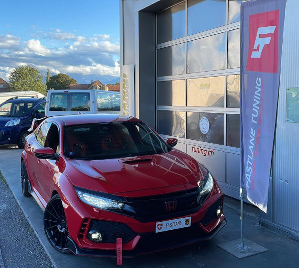 Ein roter Honda Civic Type R FK8 mit Stage 2 plus Tuning und Hardware steht neben der Fastlane Tuning Schweiz Flagge.