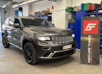 A charcoal grey Jeep Cherokee V6 diesel stands next to the Fastlane Tuning Schweiz GmbH banner.