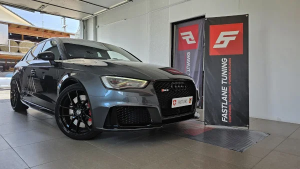 Ein anthrazitfarbener Audi RS3 steht neben dem Banner der Fastlane Tuning Schweiz GmbH