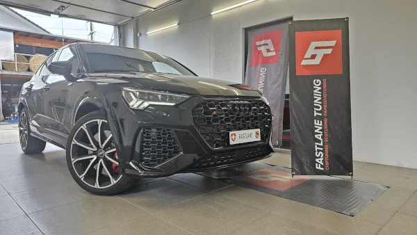 Ein schwarzer Audi RSQ3 steht neben dem Banner von Fastlane Tuning Schweiz