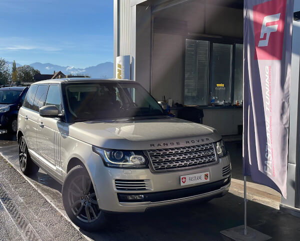 Ein goldfarbener Range Rover SDV8 steht neben der Fastlane Tuning Schweiz Flagge