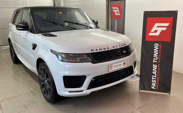 Ein weißer Range Rover 3.0 SDV6 Diesel steht neben dem Banner der Fastlane Tuning Schweiz GmbH