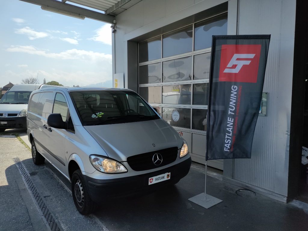 Ein silberner Mercedes Benz Viano Transporter steht vor der Garage neben der Fastlane Tuning Schweiz Flagge