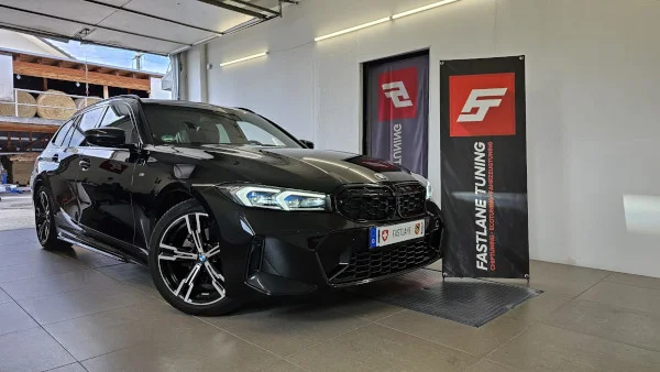 Ein schwarzer BMW G20 320d Kombi steht neben dem Banner der Fastlane Tuning Schweiz GmbH