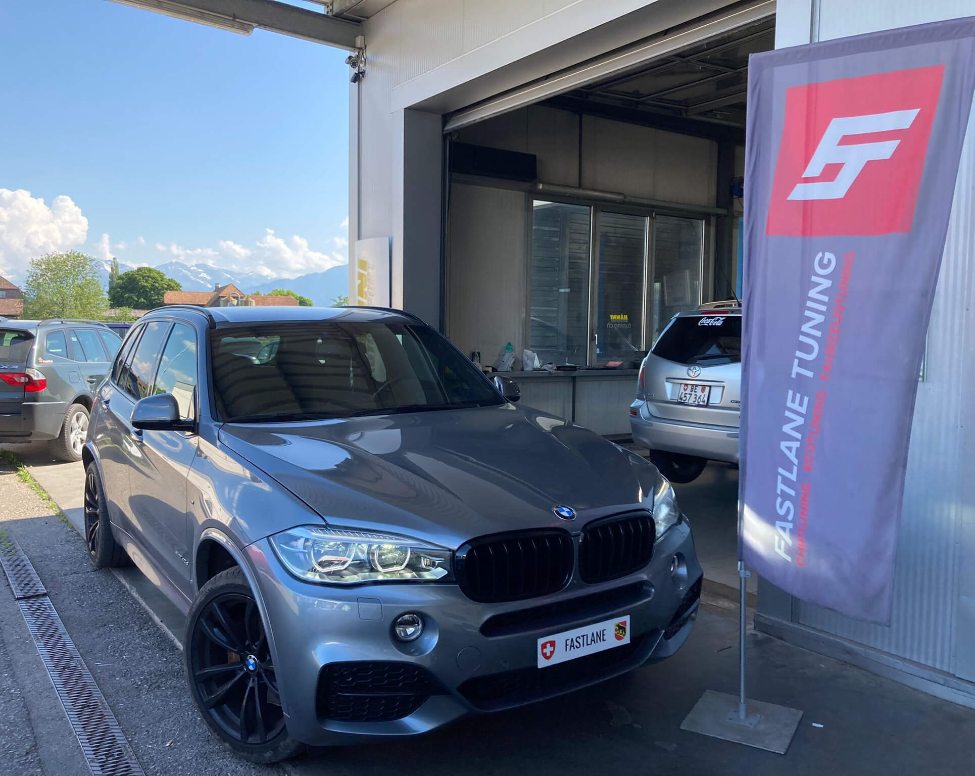 ein grau BMW X5 40d steht neben das Fastlane Tuning Schweiz Flagge