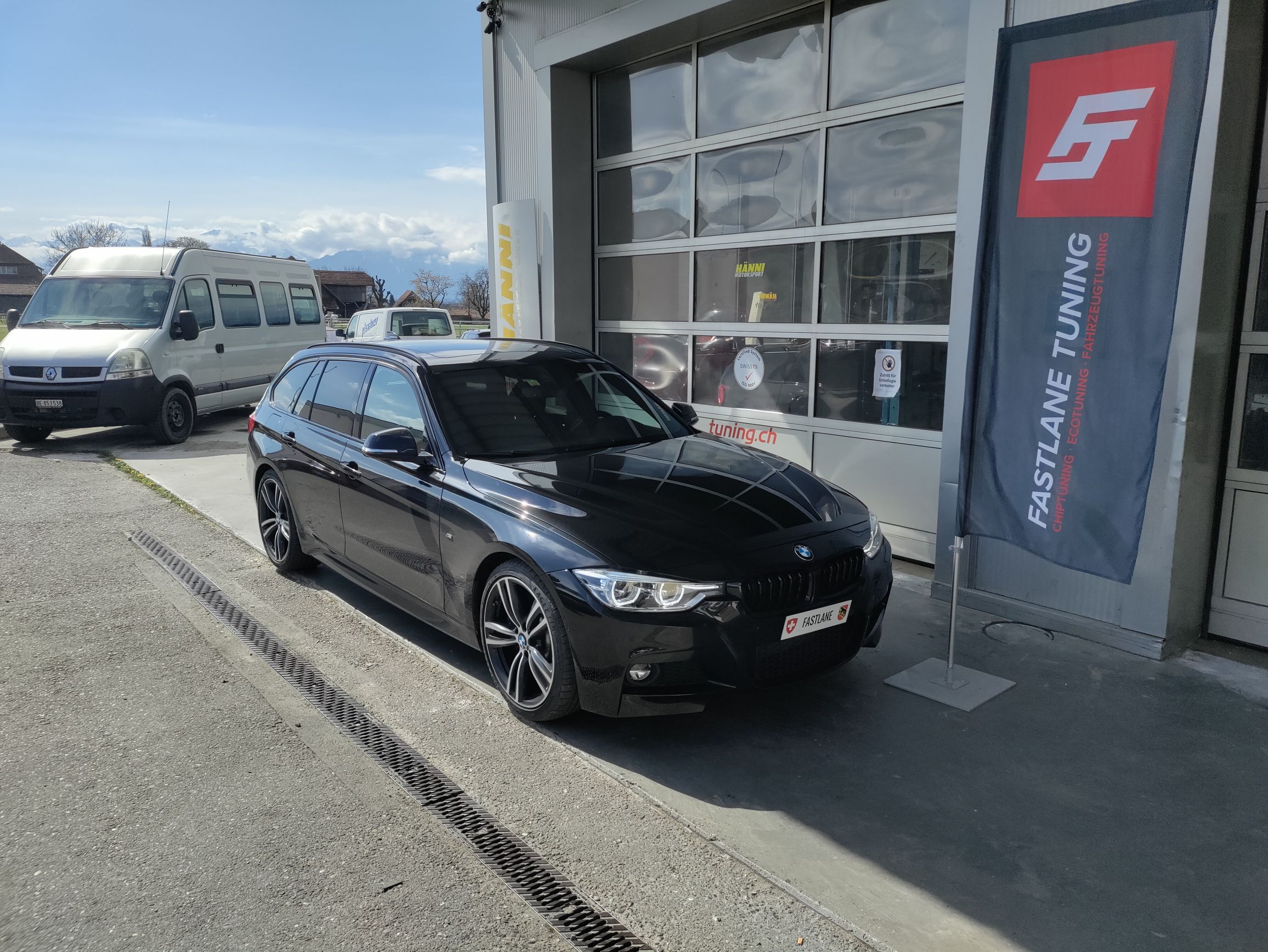 Ein schwarzer BMW F Series 428i Kombi mit B48 Motor steht vor der Garage neben der Fastlane Tuning Schweiz Flagge.