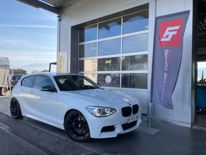 Ein weisser BMW M135i steht vor der Garage von Fastlane Tuning Schweiz.